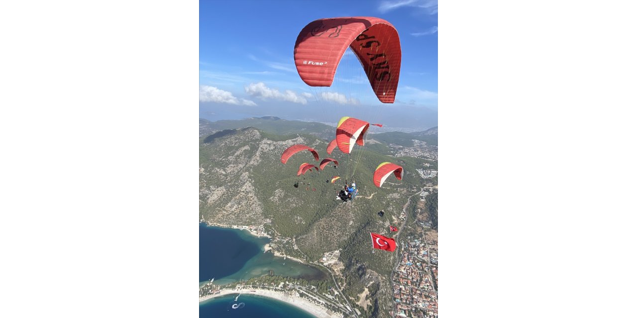 Fethiye'de üniversite öğrencileri Türk bayraklarıyla yamaç paraşütü atlayışı yaptı