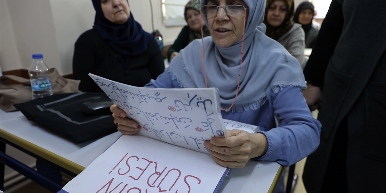 Kur'an kursu öğreticisi, az gören kursiyere ayetleri büyük harflerle yazarak destek veriyor