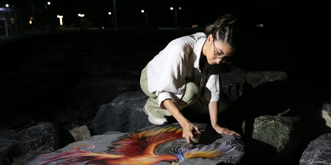 Hatay'da depremzede ressam sahil kenarındaki kayaları renklendiriyor