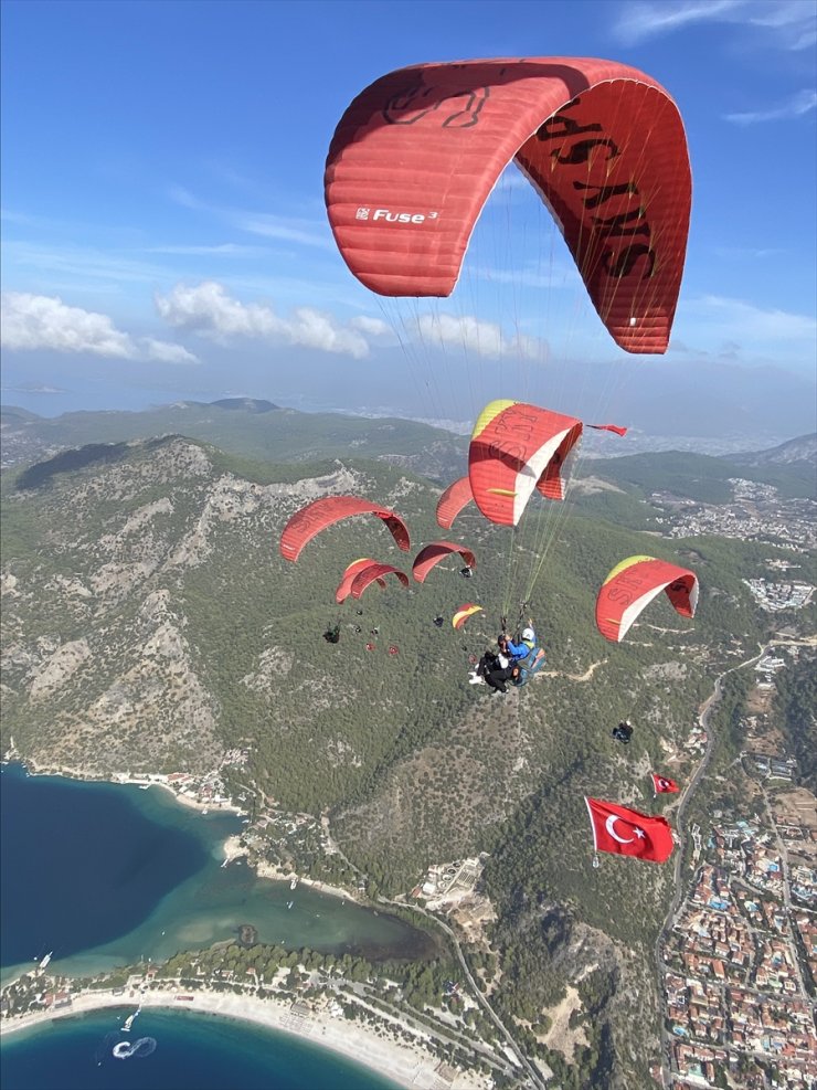 Fethiye'de üniversite öğrencileri Türk bayraklarıyla yamaç paraşütü atlayışı yaptı