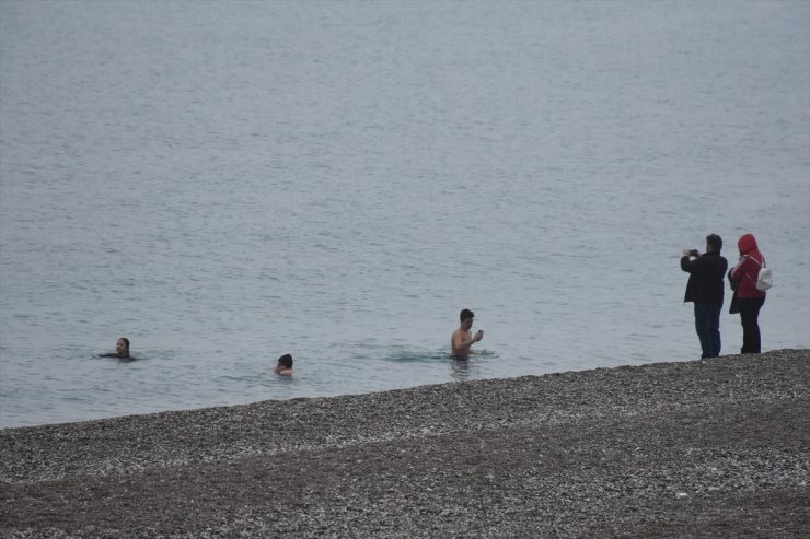 Antalya'da bazı kent sakinleri ve turistler yağışa rağmen denize girdi